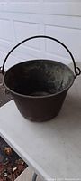 Full view of antique copper bucket showing interior and handle attached to rim