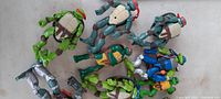 Top view of seven Ninja Turtles action figures in various poses, showing mask colors and accessory weapons, clean and lightly used condition.
