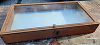 Solid wood display case with clear glass top, closed view.