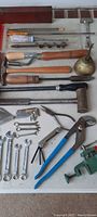 Overview of hand tools showing wooden-handled drills, brass hanging scale, hammer, and various small hand tools including pliers and wrenches.