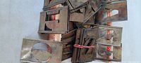 Bundles and loose antique tin brass letter stencils with uppercase letters and numbers, showing patina and use wear.