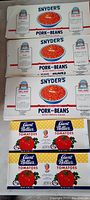 Sheets of Snyder's Pork and Beans can labels stacked and laid out showing the full design including the product name, consignment details, and tomato sauce illustration.