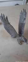 Top view showing eagle sculpture with wings spread wide, detailed feather patterns visible.