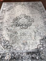 Full view of gray, blue, and beige floral area rug showing central medallion and border.