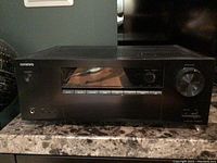 Front overview of the Onkyo AV receiver showing buttons, display and large volume knob.