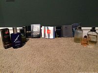 Full set of assorted men's colognes and samples arranged on carpet floor showing the different bottles and packaging from all brands in the lot.