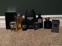 Full lot showing seven cologne bottles of varying sizes and brands on carpet.