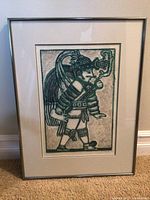 Full view of framed art print depicting indigenous figure with traditional dress and pipe, showing frame condition.
