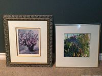 Two framed art prints displayed side by side; left print shows pink floral bouquet in a decorative frame; right print shows colorful botanical foliage with simpler dark frame.