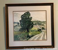 Framed watercolor painting of a rural landscape with tree, road, and hills, showing full artwork within wooden frame.
