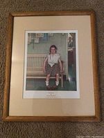 Framed Norman Rockwell art print showing girl on bench and man in kitchen background.
