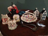 Full view of all decorative items arranged on table, including miniature houses, ceramic basket, silver spoons, blue fish, and bird figurine