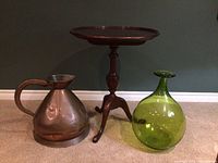 Photo of the cherry wood tripod table, large green glass vase, and copper pitcher on floor against a dark wall.