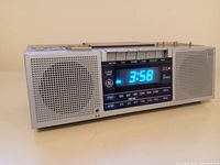 Front angled view of the stereo cassette AM/FM clock radio showing aqua blue clock display and front speakers.