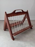 Front angle view showing teak wood frame and vertical rope cords suspended to hold magazines