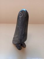 Front view of the soapstone snowy owl carving showing the rounded head, etched eyes, and small feet details.