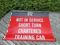 Roll sign displayed showing red side with white service text: NOT IN SERVICE, SHORT TURN, CHARTERED, TRAINING CAR, and route 312.
