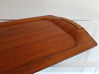 Close-up side view of mid-century modern walnut serving tray showing cane wrapped handle detail and smooth wood grain surface.