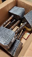Seven Thunder God hammers with textured grey hammer heads and brown handles inside cardboard box