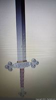 Close-up image of a British Broad Epee sword blade and hilt, showing decorative jewelled crossguard and detailed blade markings.