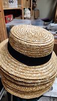 Stack of Anne straw hats with black bands close-up