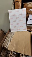 Stack of white and natural kraft paper bags with jute handles visible on top.