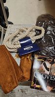 Image of faux suede brown gloves, thick coiled cream rope, and packaging for warrior-style gloves included in the lot.