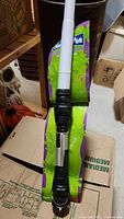 Silver and black hilt light saber with white blade against cardboard packaging