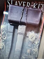 Close-up photo of one vampire slayer kit showing a wooden mallet, stake, cross and flask in packaging.