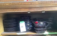 Shelf with stack of dark red glass dessert plates, bowls, and rectangular dishes