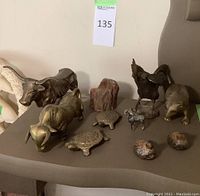 Photo showing entire collection of brass animal figurines, turtles, and pieces of petrified wood on table.