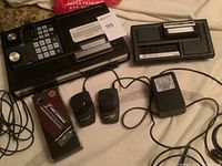 Top view of the ColecoVision console showing numeric keypad and joystick ports, Expansion Module 1 console section, power adapter, two paddle controllers, and Video Command rapid fire button in box.