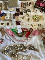 Overview of various necklaces, brooches, beads and stick pins laid out on fabric