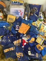 Wide view of assorted Rams apparel, hats, bags, cushions and fan items laid out on carpet