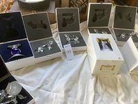 Overview of six white presentation boxes each holding a crystal figurine, some boxes show wear