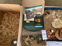 Wide view showing multiple small crystal and stone animal sculptures in boxes with some display packaging and catalog materials