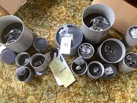 All grey cylindrical boxes with foam inserts laid out on carpet showing multiple items