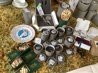 Overview of Swarovski figurine cylinders, giraffe box, hedgehog, Harmony Kingdom boxes and calendar plate on carpet