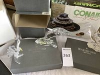 Three crystal sculptures displayed on Waterford and Swarovski boxes