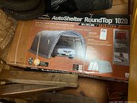Box packaging front showing ShelterLogic AutoShelter RoundTop 1020 branding and product image