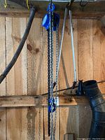 Power Fist triangle chain hoist hanging on a wooden wall with multiple chains and hooks visible.