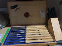 Wooden box open showing Freud chisels with wooden handles and metal blades on blue felt lining, some rust seen on blades.