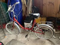 Full left-side view of red Pony folding bicycle showing frame, saddle, pedals, fenders, rear rack and flat tires