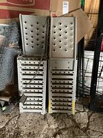 Pair of grey metal foldable loading ramps with traction holes, viewed top down, folded and chained together