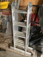 Full view of folded aluminum scaffolding ladder showing multiple folding sections and stabilizer feet.