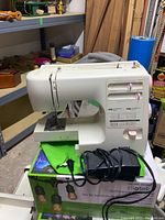 Kenmore sewing machine model 385.16782 with power cord and foot pedal on a table with a green cloth underneath.