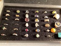 Top view of all rings displayed in black felt tray, showcasing variety of colors and styles