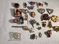 Full overview of all 35 vintage costume pins laid out on white textured fabric.