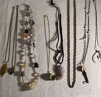 Full view of all 10 assorted costume jewelry pieces laid flat, showing variety of chains, pendants, and materials.