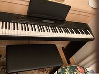 Casio CDP 230R digital keyboard with bench and foot pedal, showing full keyboard and bench from above.